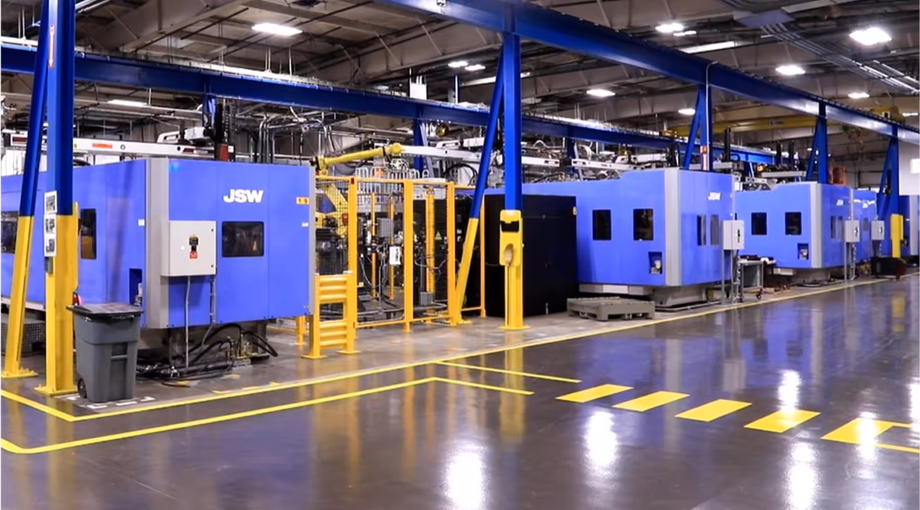 Row of large blue JSW industrial machines inside a clean, well-lit manufacturing facility.